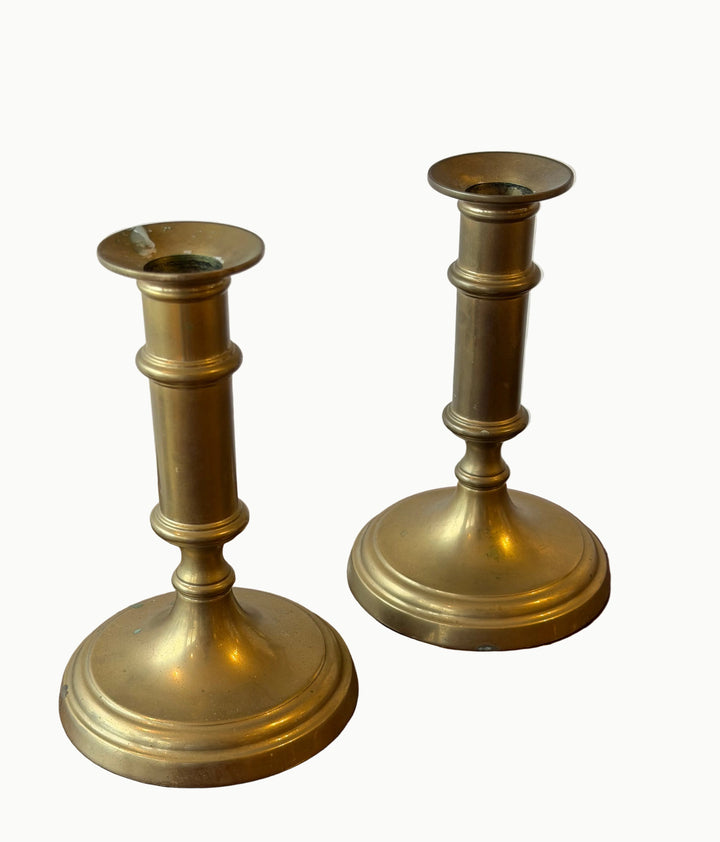 Pair of gold candle holders on a wooden surface with a white background