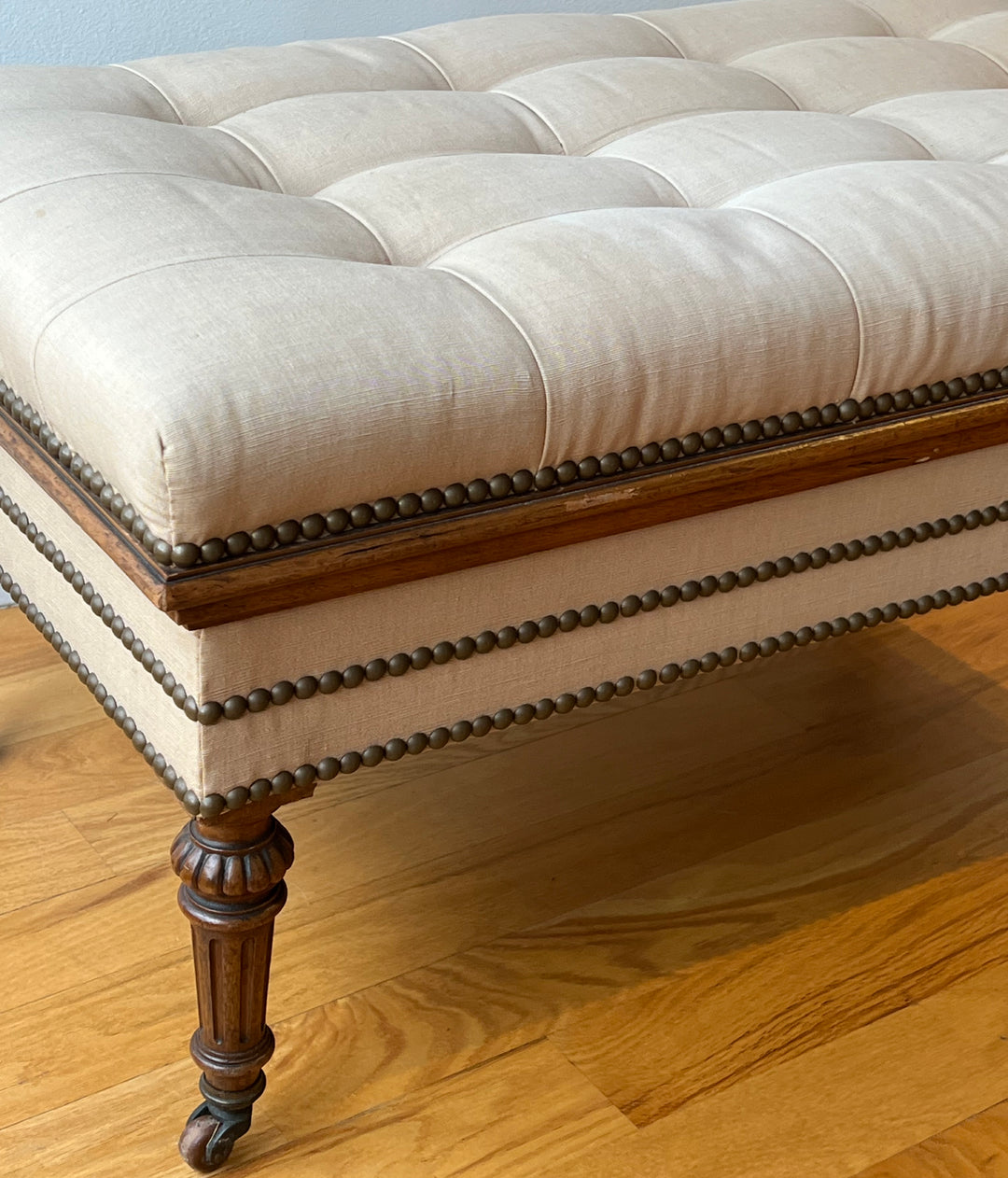 Antique English Tufted Storage Bench on Fluted Legs with Casters detail showcasing tufted upholstery and nailhead trim.
