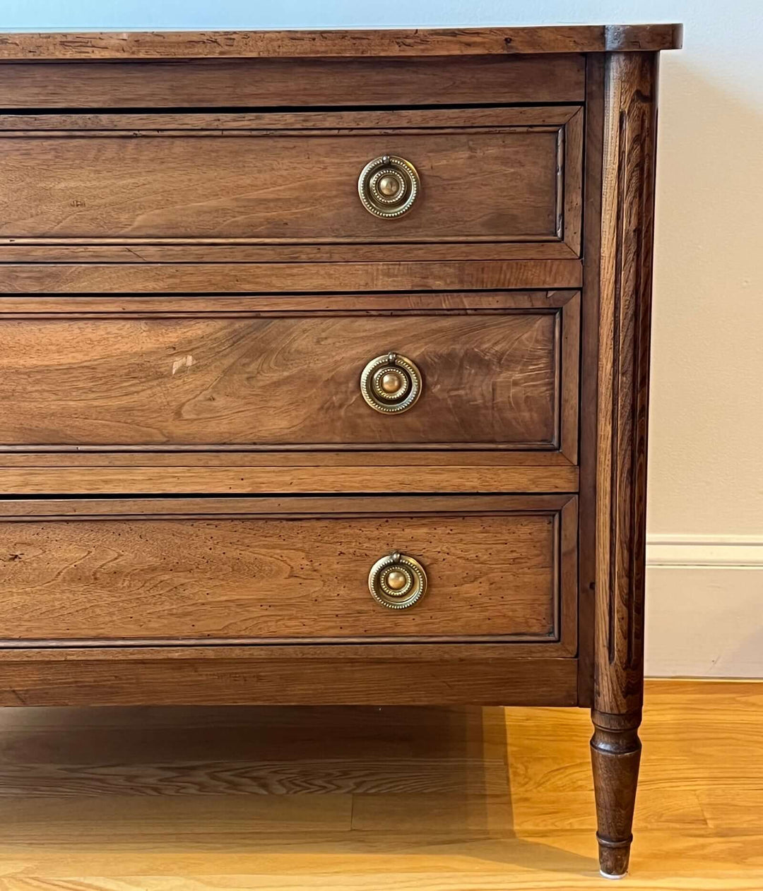 Early 19th Century French Louis XVI Style Walnut Three-Drawer Commode with brass-ring pulls and fluted stiles.