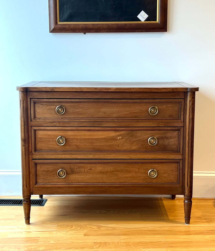 Early 19th Century French Louis XVI Style Walnut Three-Drawer Commode showcasing brass-ring pulls and tapered legs.