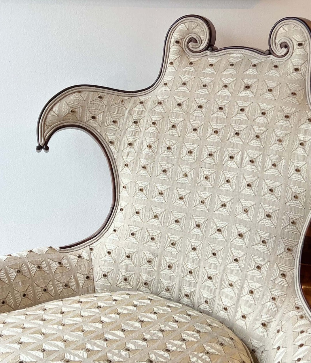 Antique Scroll-Crest Upholstered Armchair in Mahagony Frame with intricate cream upholstery and elegant scroll back.