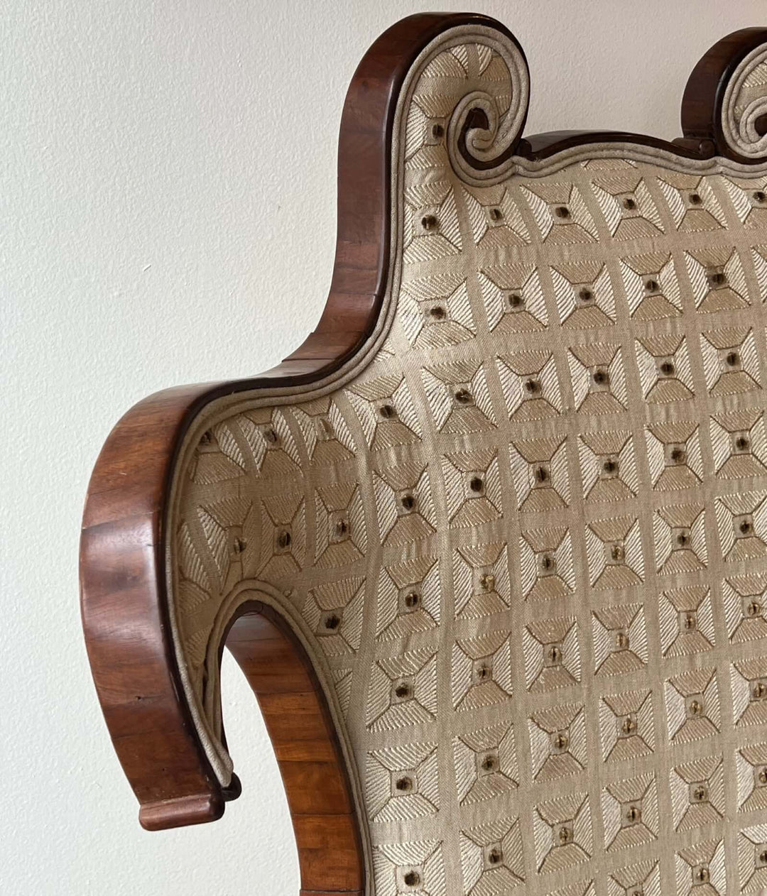 Antique Scroll-Crest Upholstered Armchair in Mahagony Frame with a detailed view of the back upholstery and wood.