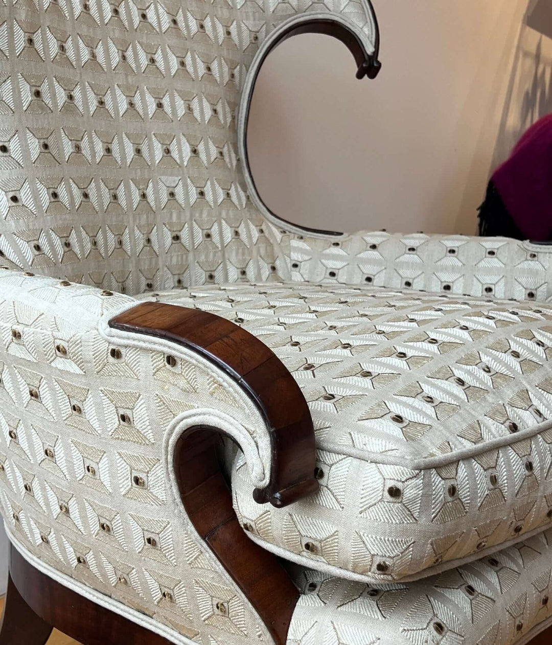 Antique Scroll-Crest Upholstered Armchair in Mahagony Frame showcasing intricate upholstery and fine mahogany details.