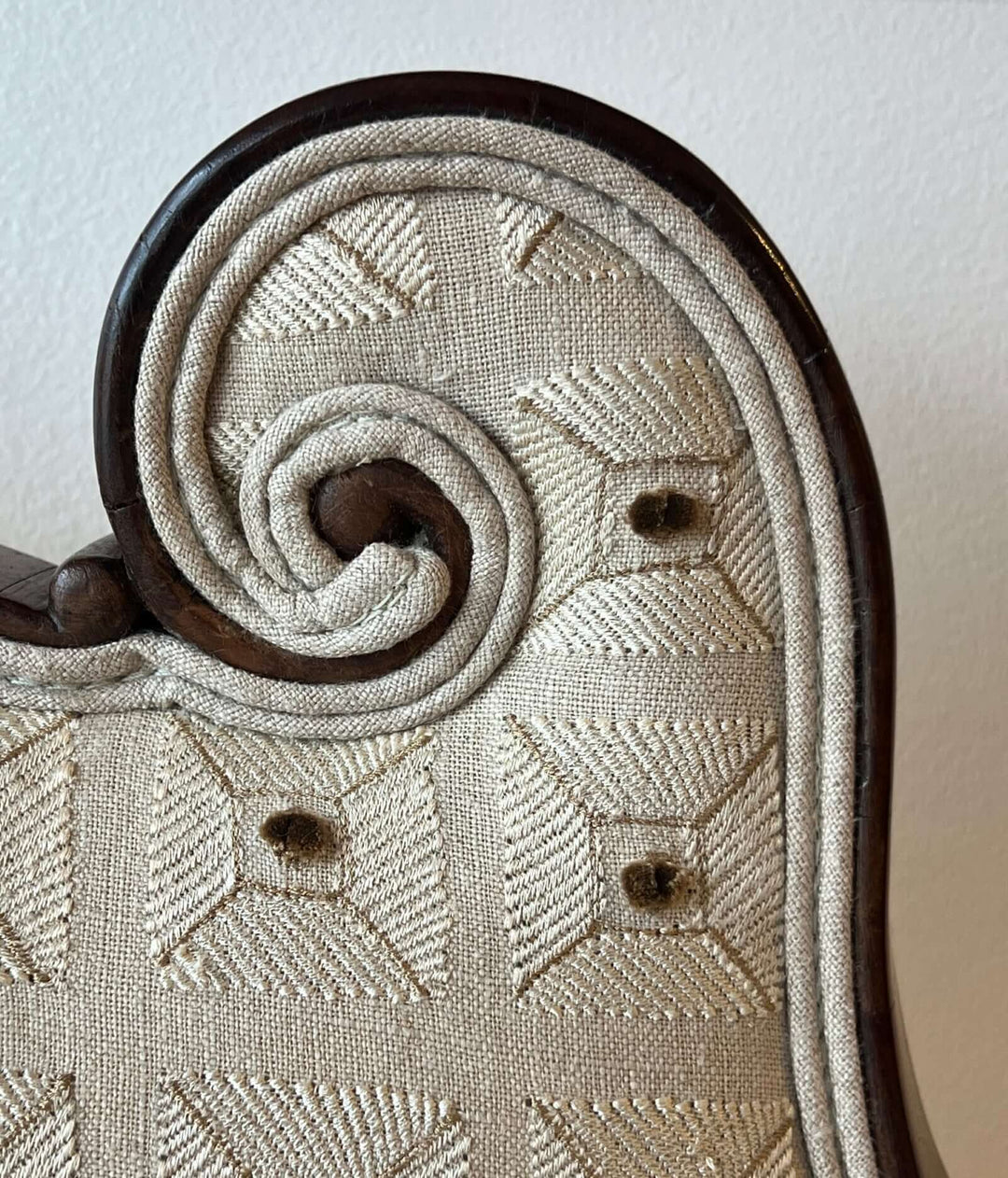 Detail of the Antique Scroll-Crest Upholstered Armchair in Mahagony Frame, showcasing the scroll design and upholstery.