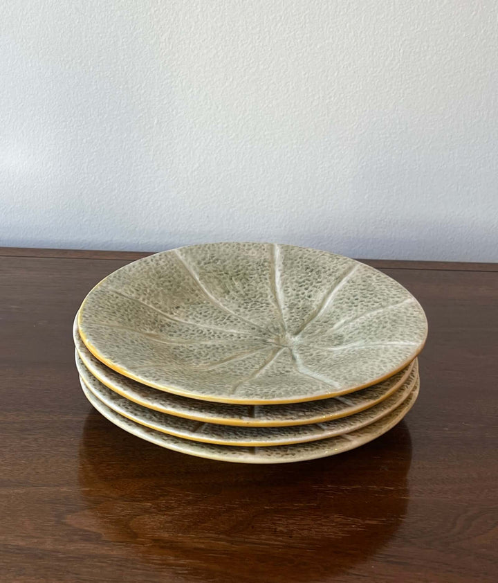 Set of Bordallo Pinheiro Melon Dessert Plates from Portugal stacked on a wooden table with a soft celadon-green glaze.