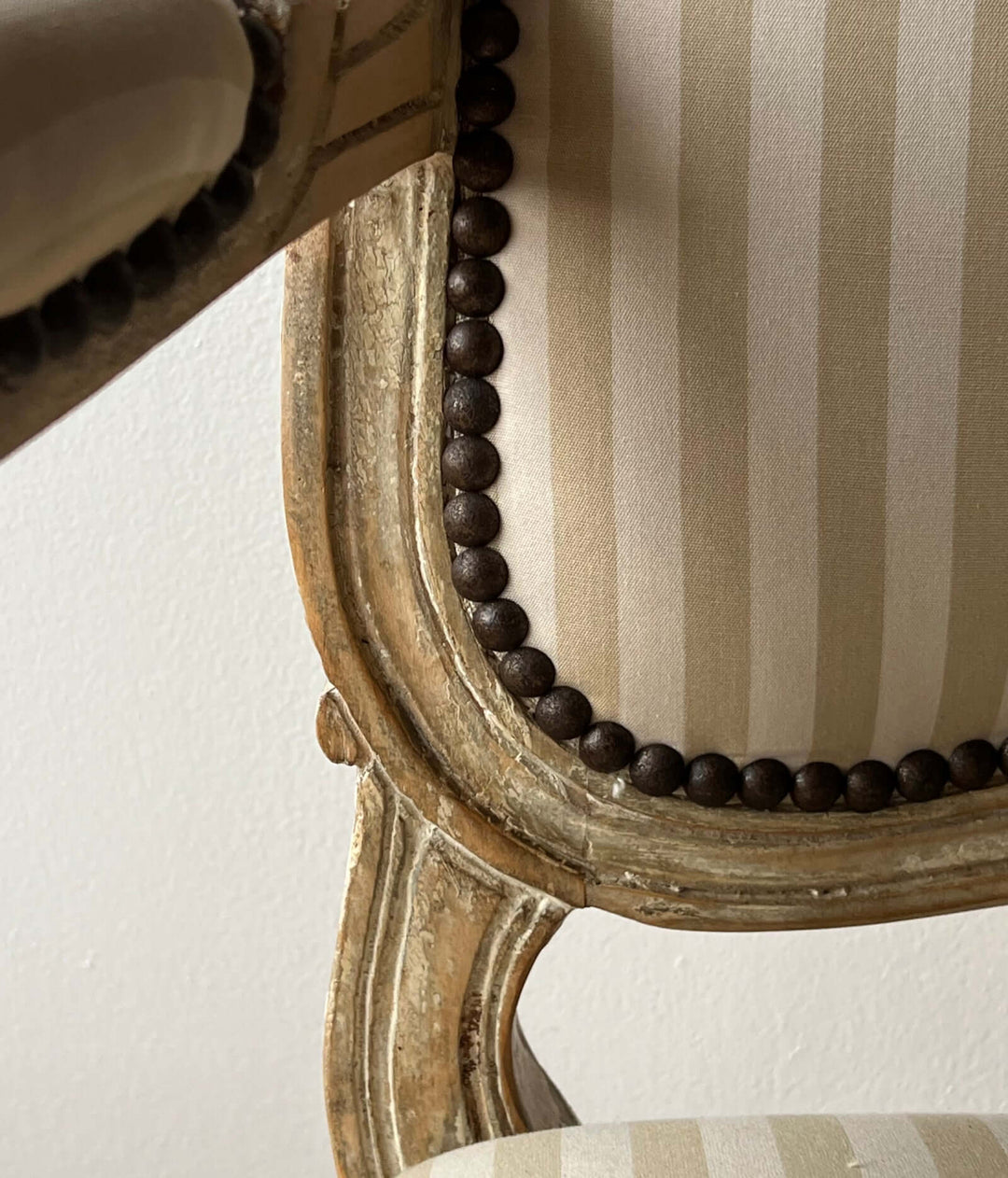 Close-up of Pair of Vintage Louis XV Style Fateuil armchairs showing the striped fabric and carved wood detail.