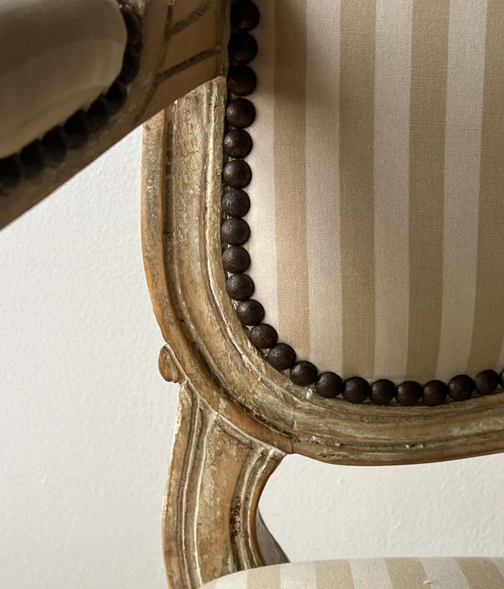 Close-up of Pair of Vintage Louis XV Style Fateuil armchairs showing the striped fabric and carved wood detail.