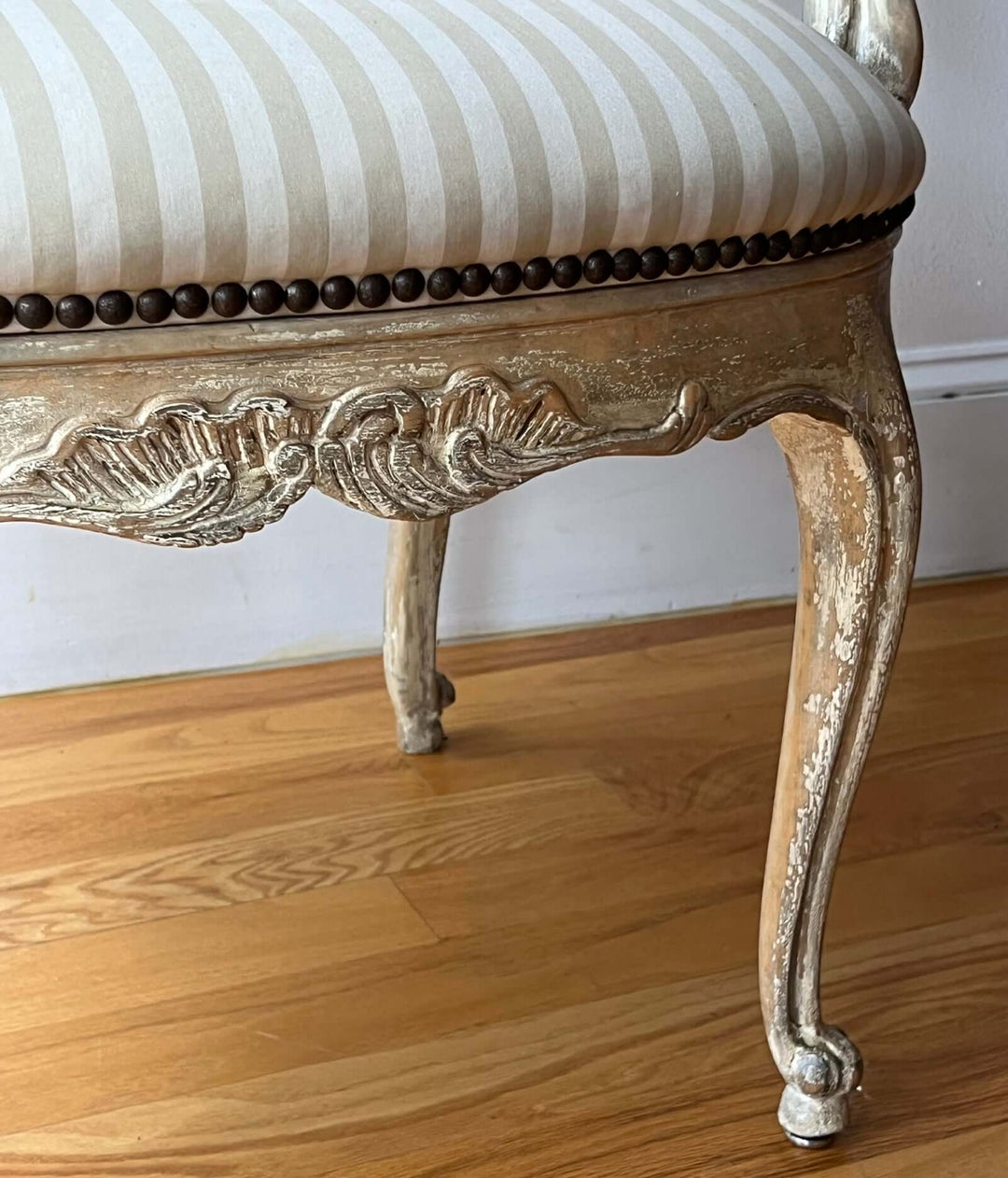 Pair of Vintage Louis XV Style Fateuil armchairs with a detailed carved leg and striped upholstery.