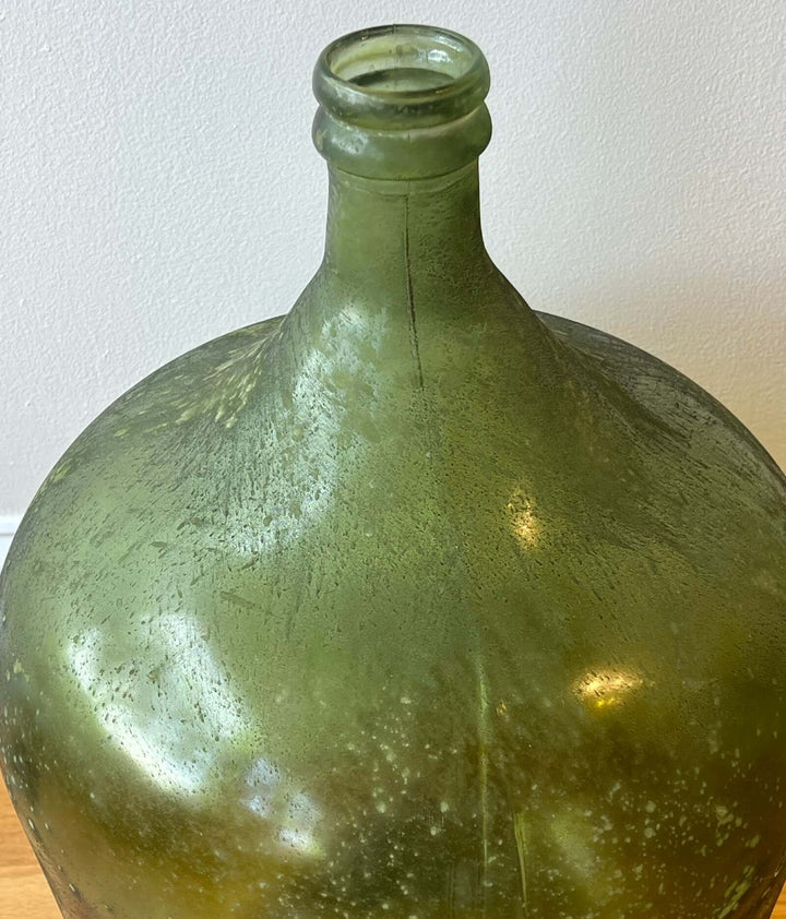 Vintage Spanish Green Demijohn Bottle with Rolled Rim, showcasing textured glass and unique bubbles.