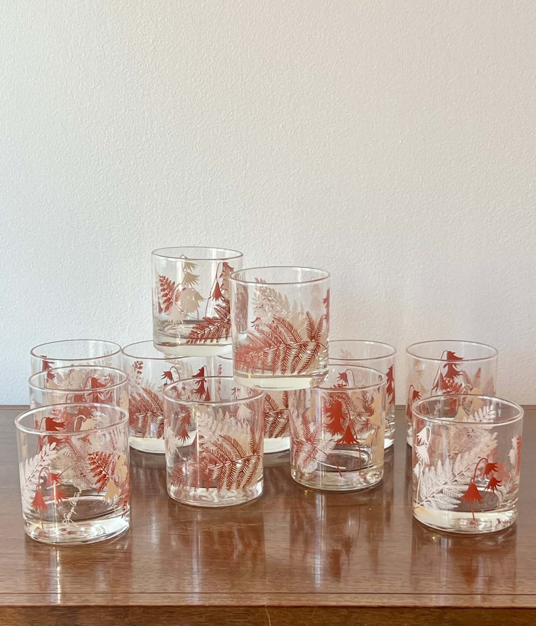 Set of glass tumblers with red floral patterns on a wooden surface.