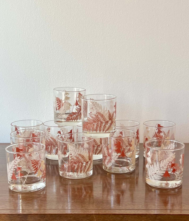 Set of glass tumblers with red floral patterns on a wooden surface.