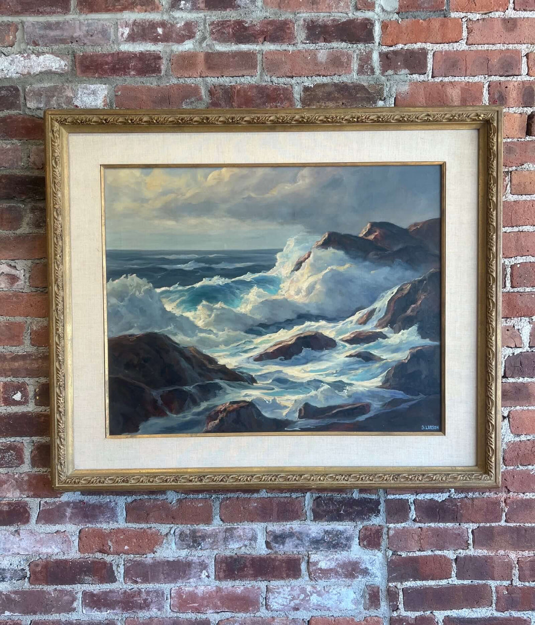 Framed painting of a seascape with waves crashing against rocks on a brick wall.