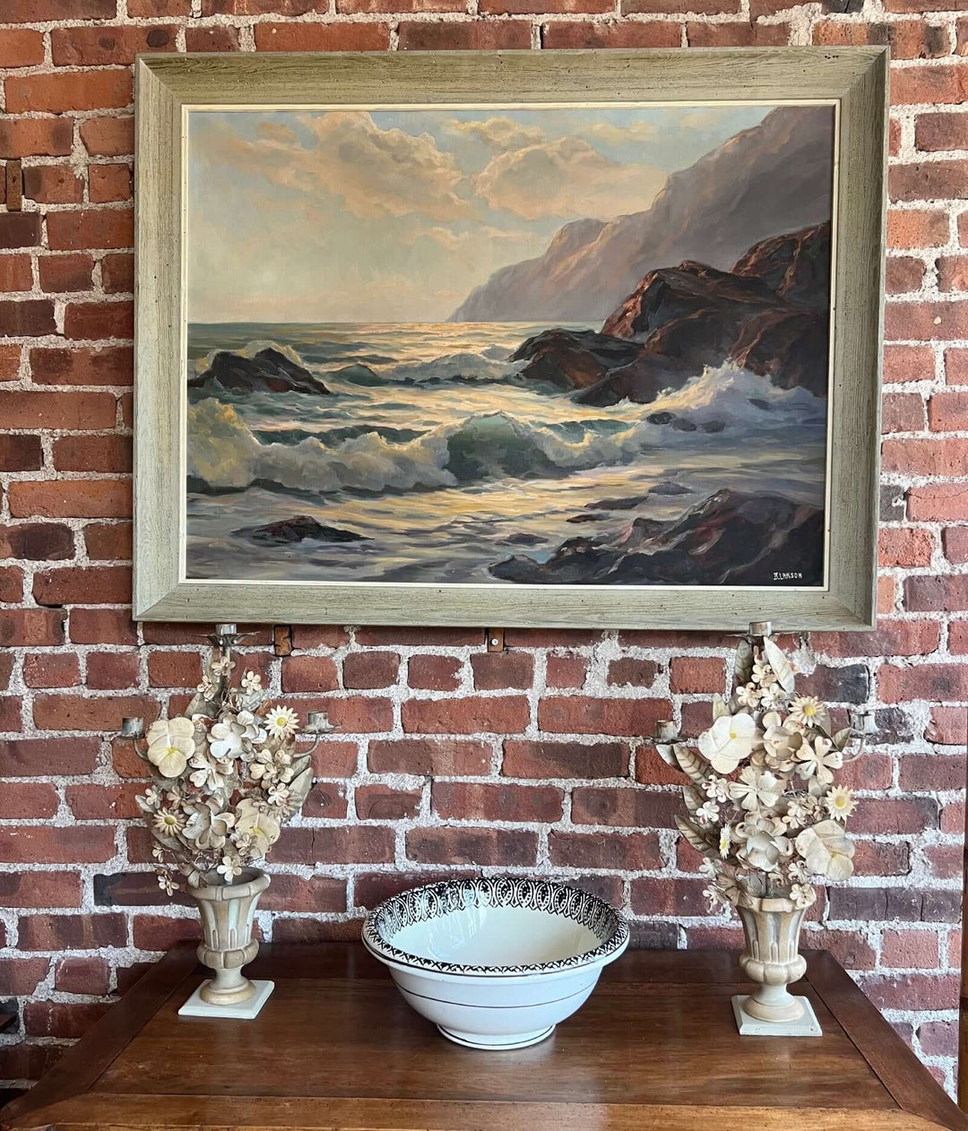 Pair of Vintage Italian Tole Floral Candelabras with a landscape painting and decorative bowl on a wooden table