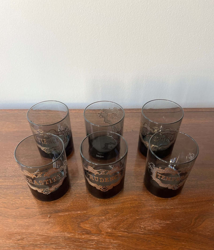 Set of six glass tumblers with branding on a wooden surface