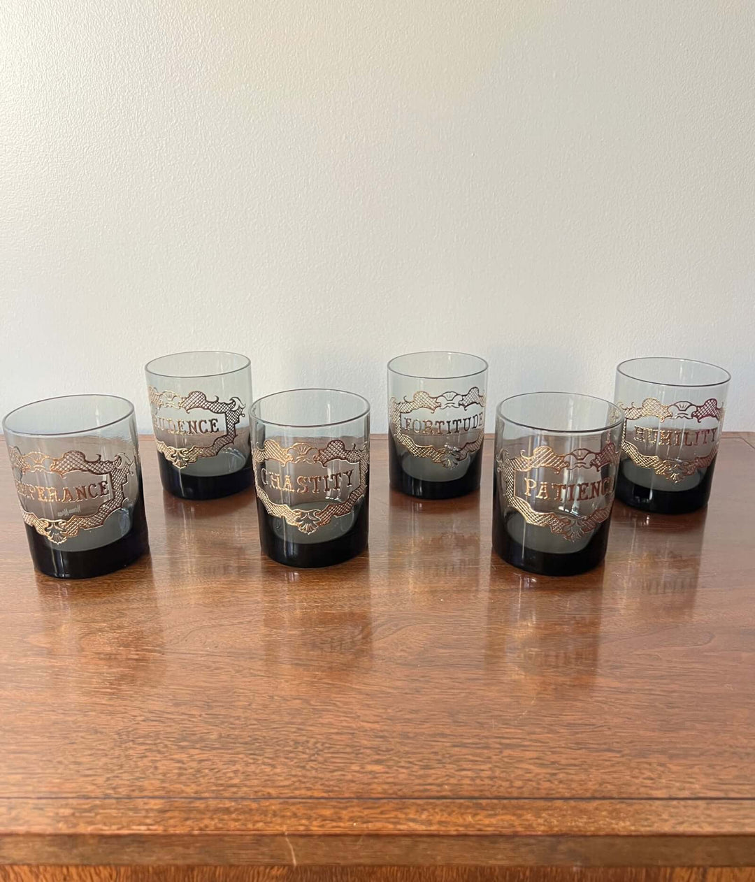 Set of six glass tumblers with branding on a wooden surface